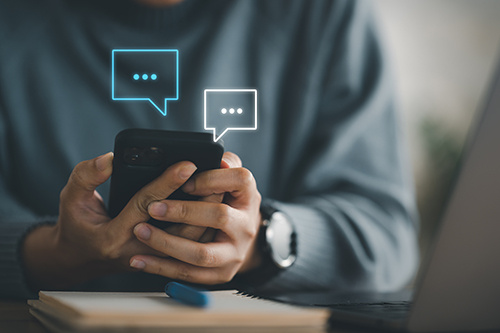 Person holding a smartphone displaying text message icons, representing the use of Azara patient outreach campaigns.