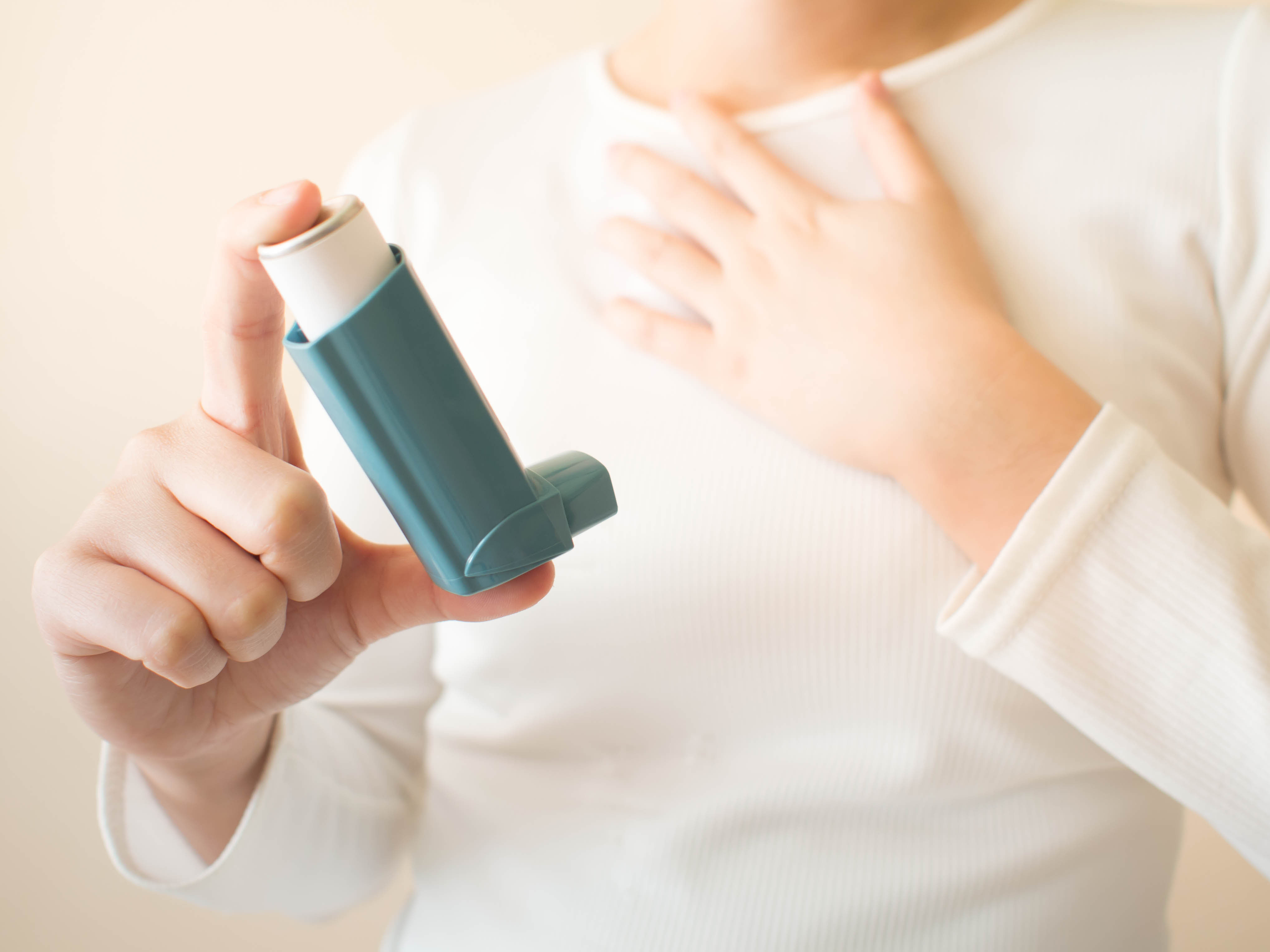 Person holding an inhaler, highlighting asthma management for Asthma Awareness Month.