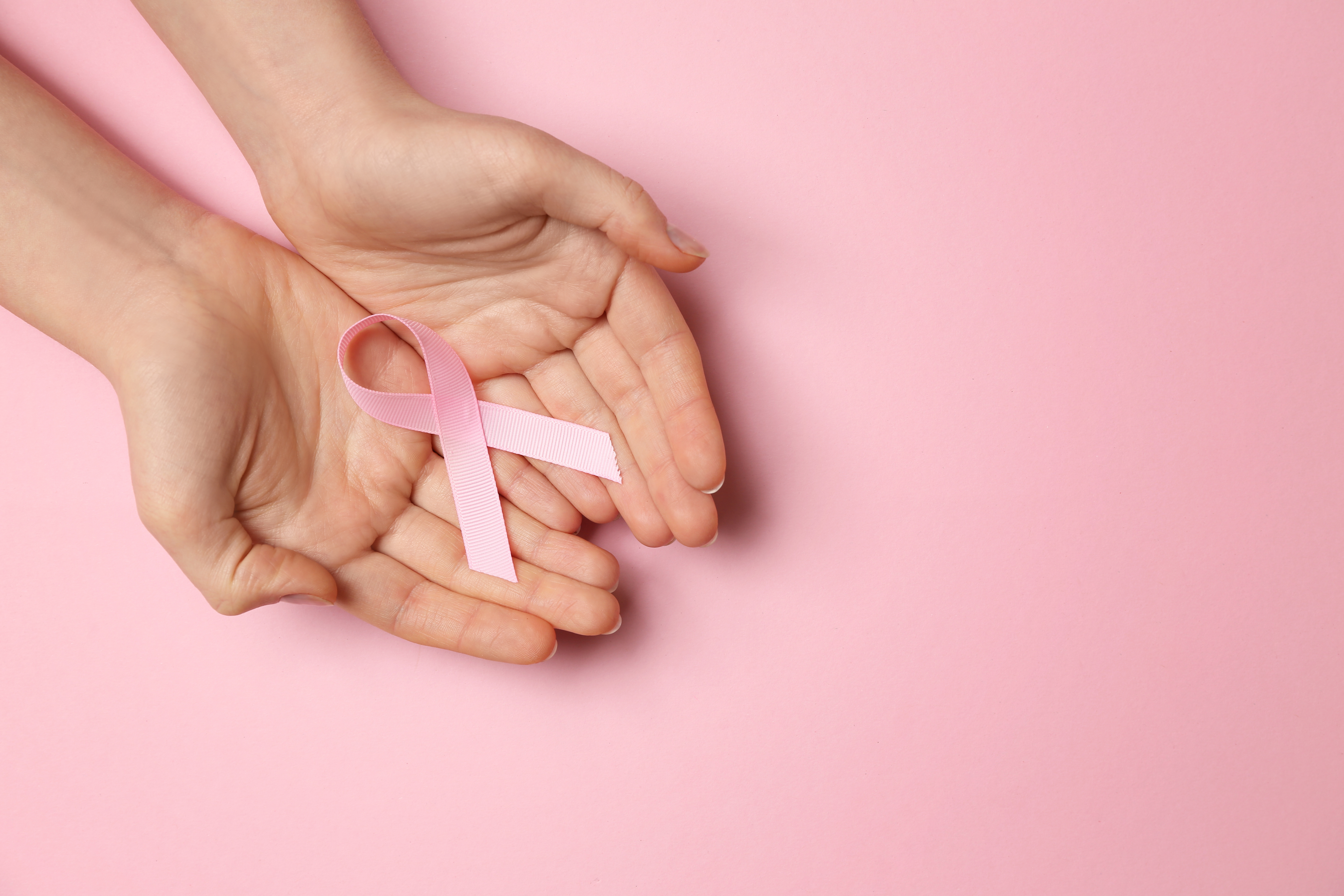 Person holding a pink breast cancer awareness ribbon