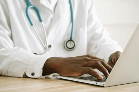 Doctor typing on a computer researching Medicaid Redetermination